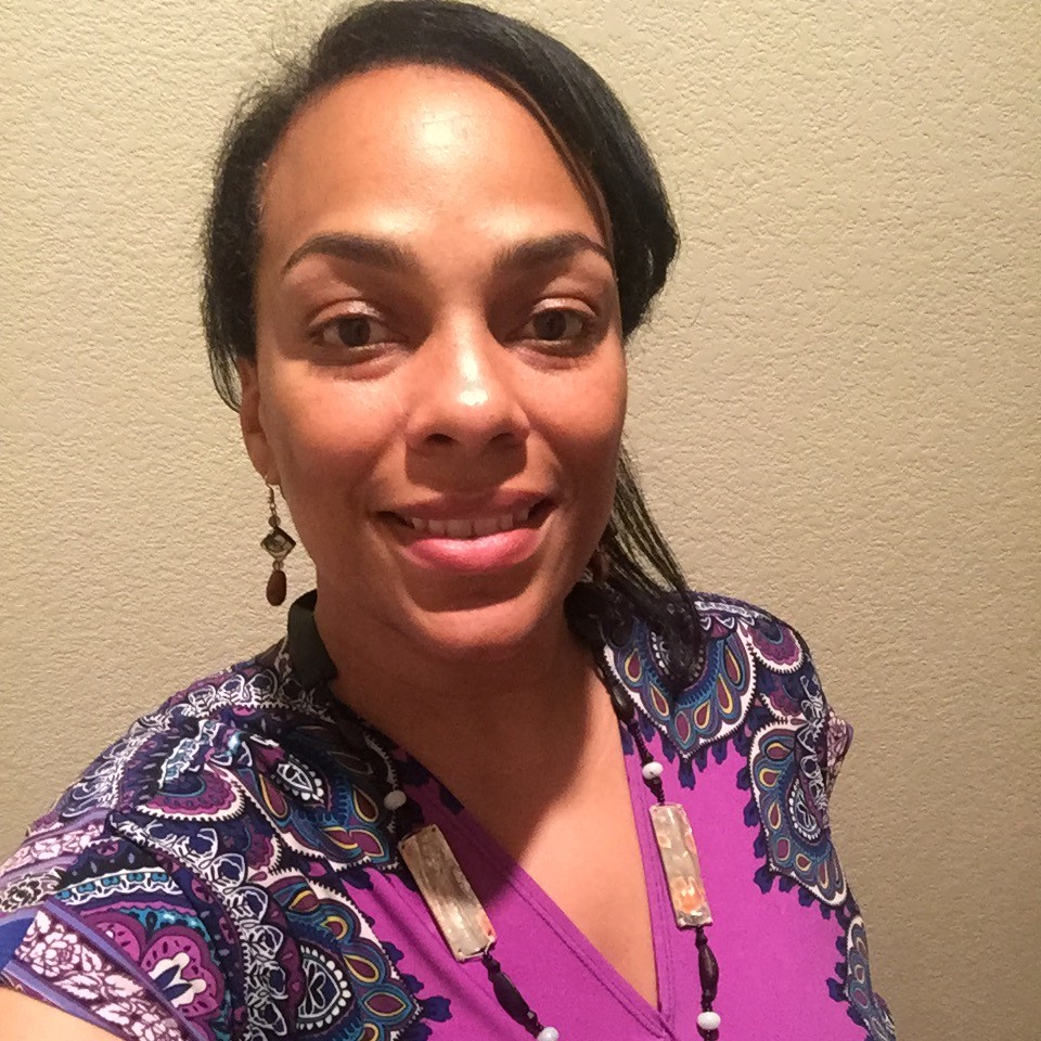 Tracy Thomas looking at camera, pink shirt traditional necklace