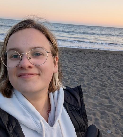 Macie Gard on a beach with the sun starting to set in the background